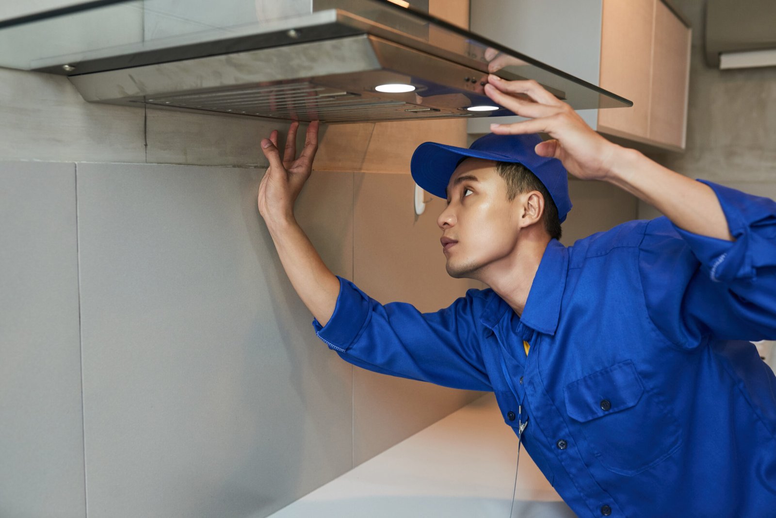 Young Vietnamese technician installing extractor hood in kitchen